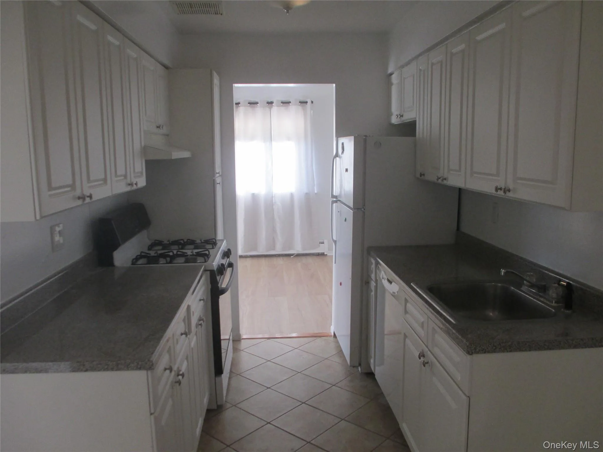 Kitchen featuring gas stove, white cabinets, ventilation hood, and light tile patterned floors Kitchen featuring gas stove, white cabinets, ventilation hood, and light tile patterned floors