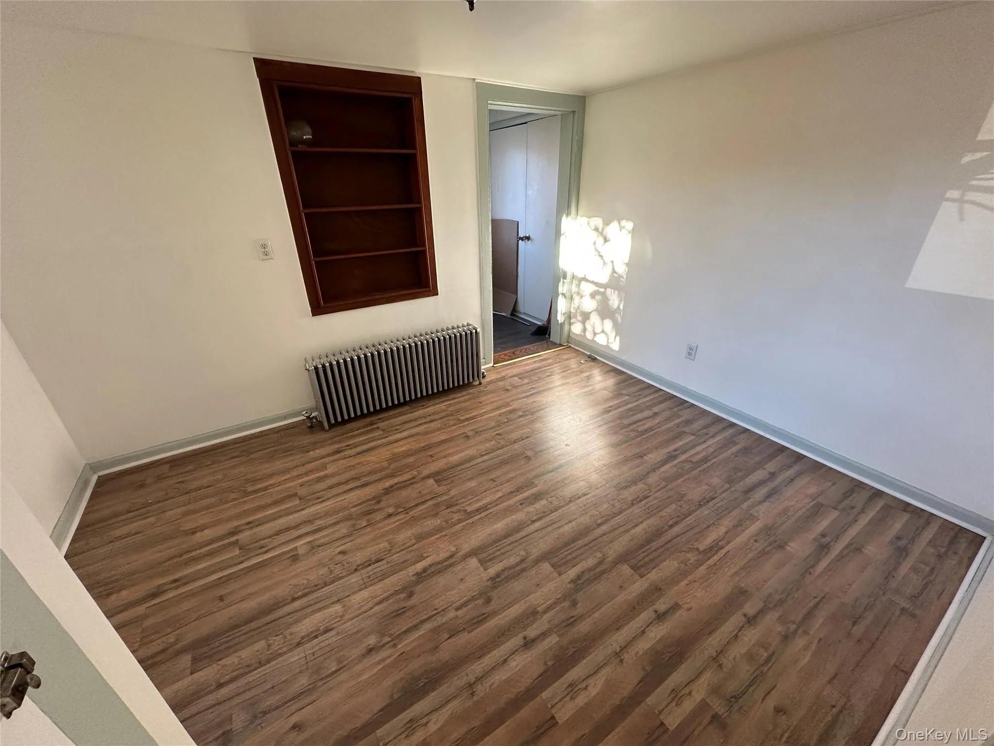 Bedroom featuring wood finished floors, built in features, and radiator Bedroom featuring wood finished floors, built in features, and radiator
