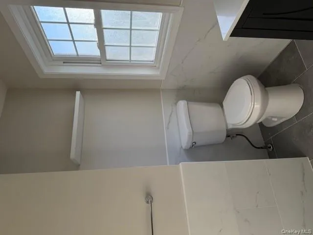 Half bathroom featuring tile walls, vanity, wainscoting, and dark tile patterned flooring Half bathroom featuring tile walls, vanity, wainscoting, and dark tile patterned flooring