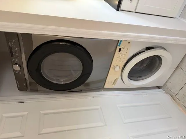 Washroom featuring light tile patterned floors and stacked washing machine and dryer Washroom featuring light tile patterned floors and stacked washing machine and dryer