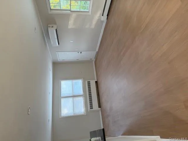 Unfurnished living room with light wood finished floors, radiator, a baseboard radiator, and crown molding Unfurnished living room with light wood finished floors, radiator, a baseboard radiator, and crown molding