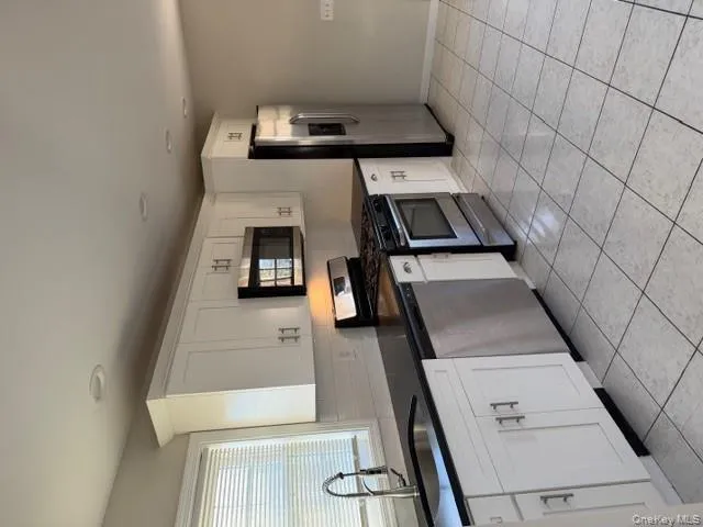 Kitchen with stainless steel range oven, white cabinets, fridge, dishwasher, and light tile patterned floors Kitchen with stainless steel range oven, white cabinets, fridge, dishwasher, and light tile patterned floors
