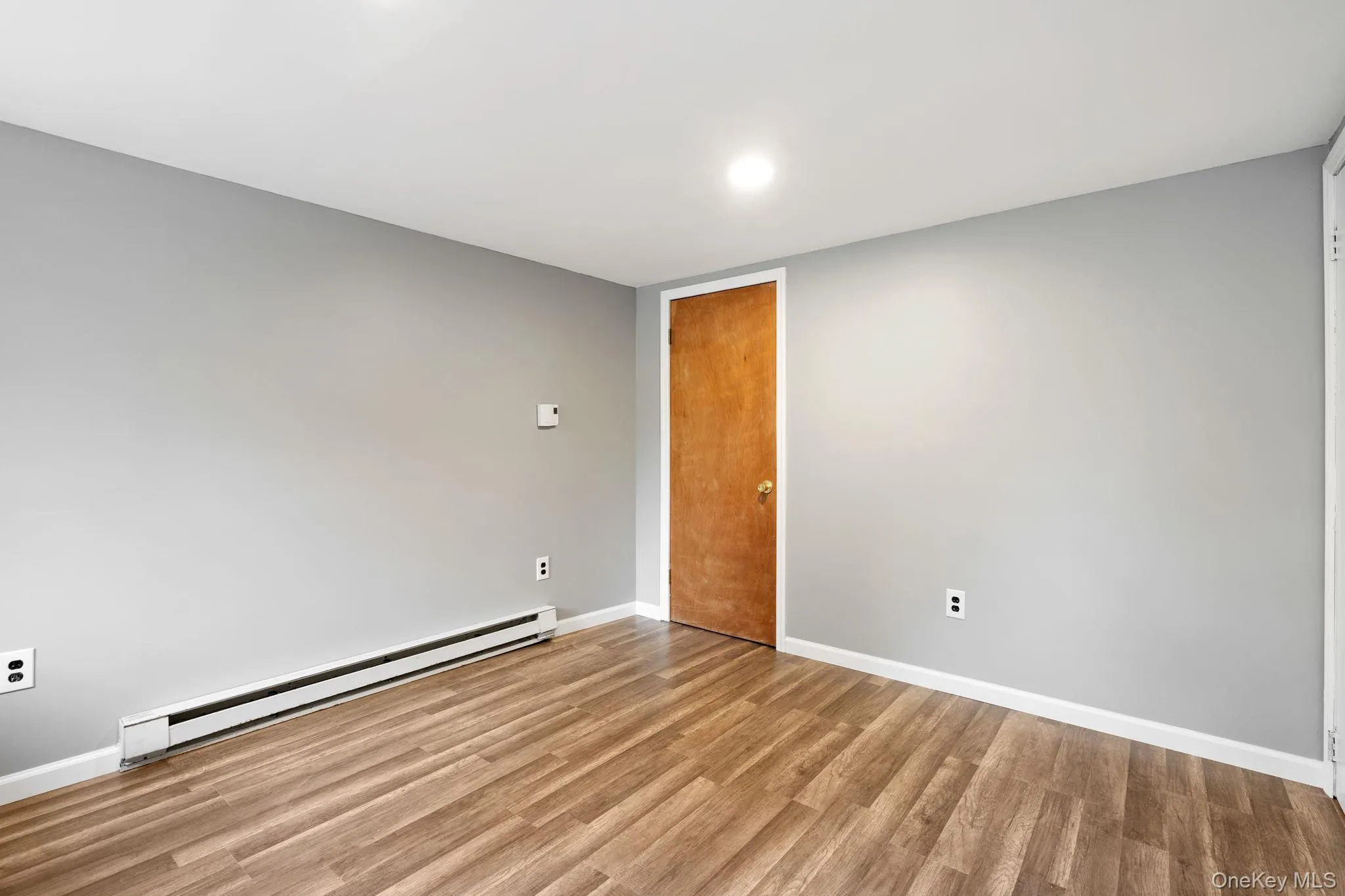 Unfurnished room with a baseboard heating unit, light wood-style flooring, and recessed lighting Unfurnished room with a baseboard heating unit, light wood-style flooring, and recessed lighting