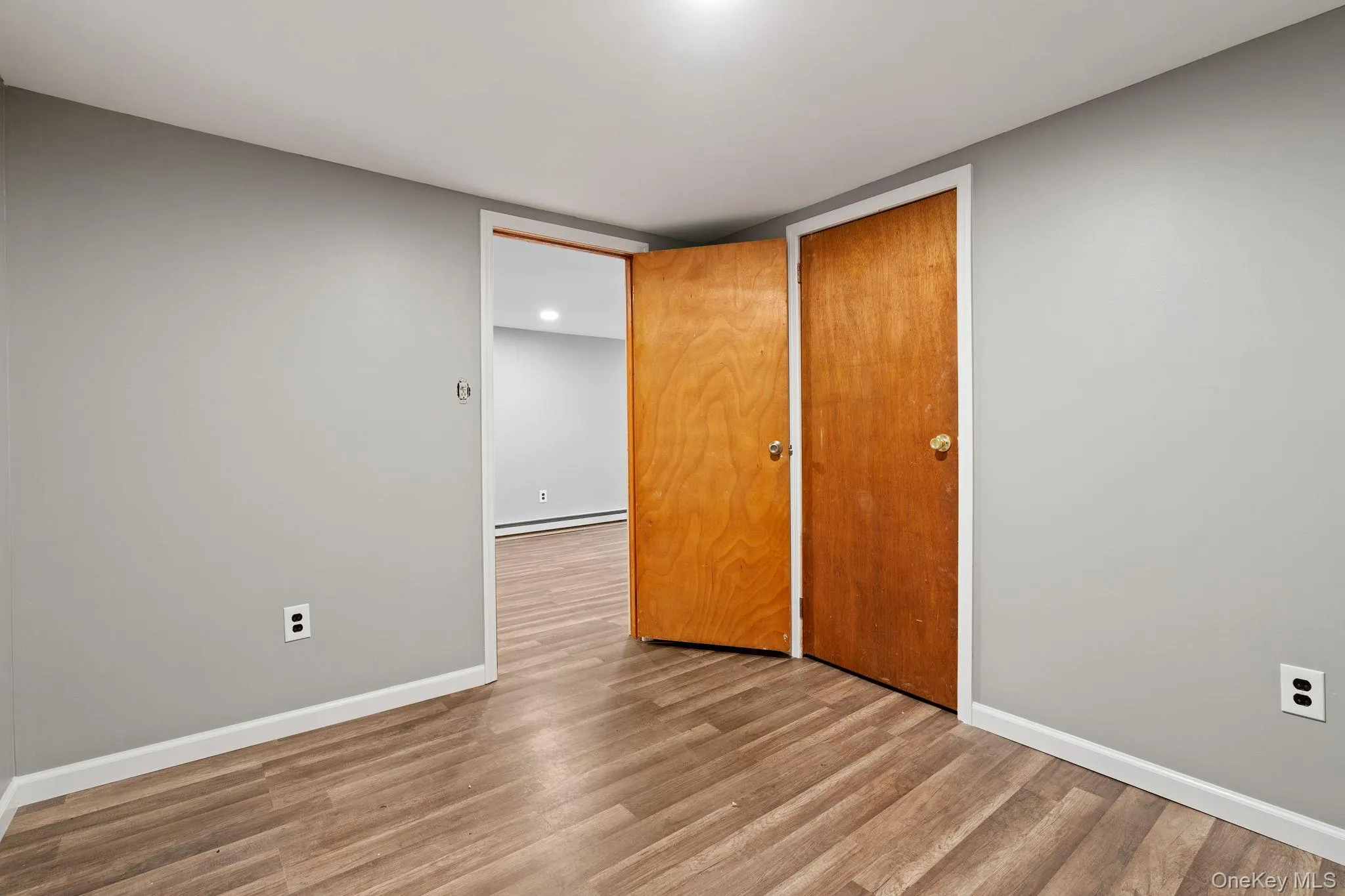Unfurnished bedroom featuring wood finished floors, a closet, and a baseboard radiator Unfurnished bedroom featuring wood finished floors, a closet, and a baseboard radiator
