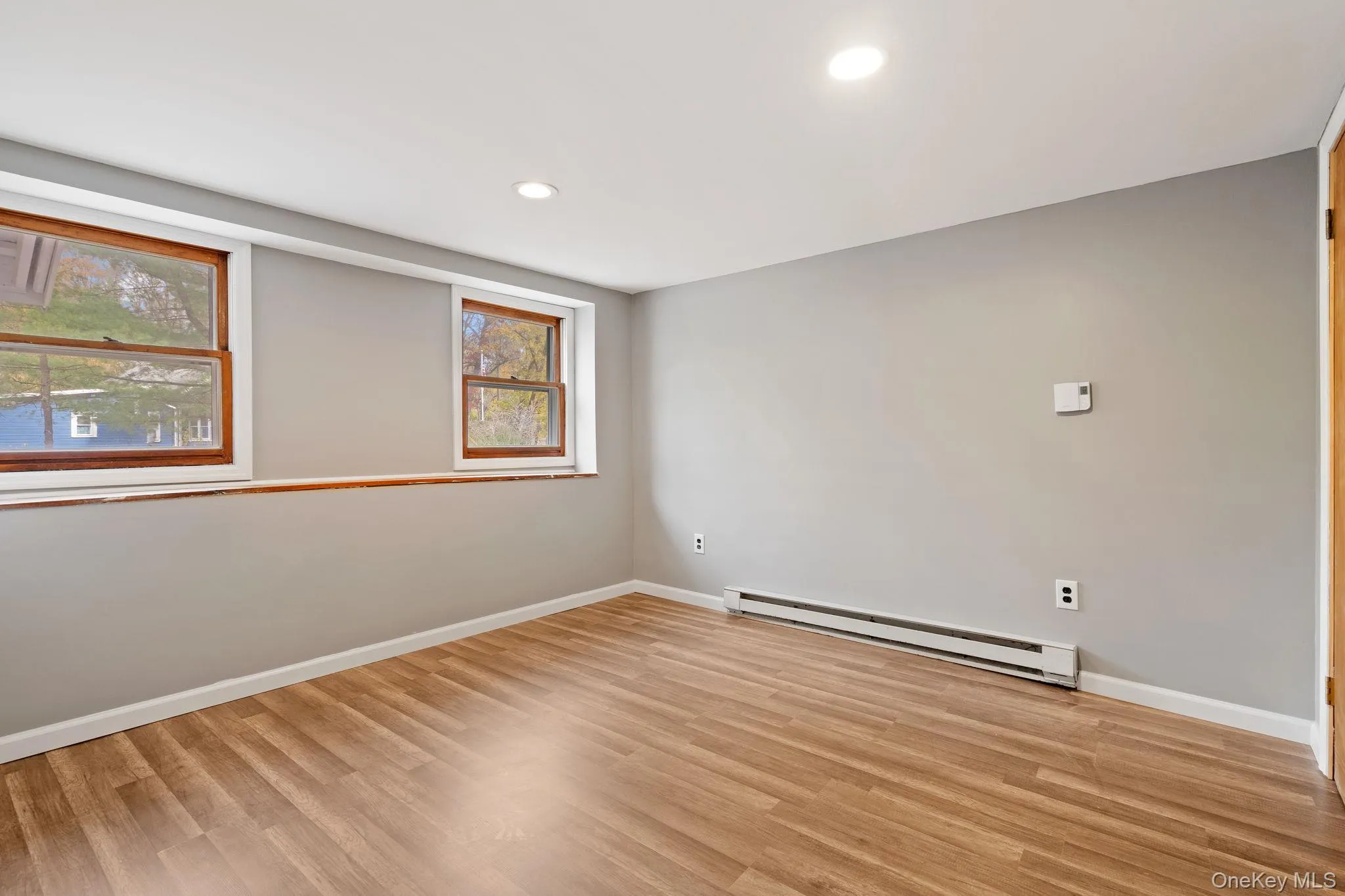 Unfurnished room with a baseboard radiator, recessed lighting, and light wood finished floors Unfurnished room with a baseboard radiator, recessed lighting, and light wood finished floors