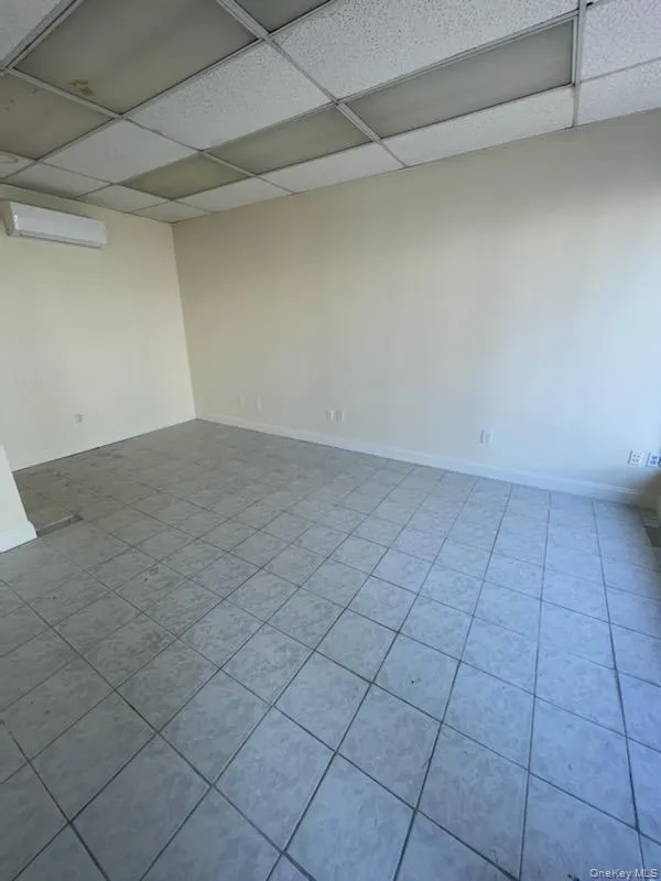 Spare room with light tile patterned flooring, a paneled ceiling, and a wall unit AC Spare room with light tile patterned flooring, a paneled ceiling, and a wall unit AC