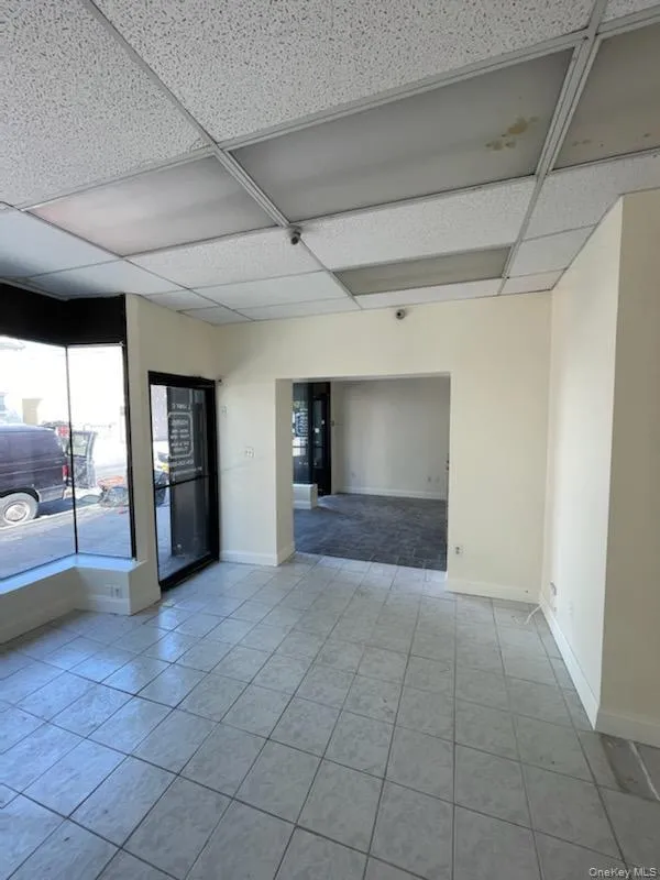 Unfurnished room with light tile patterned floors and a drop ceiling Unfurnished room with light tile patterned floors and a drop ceiling