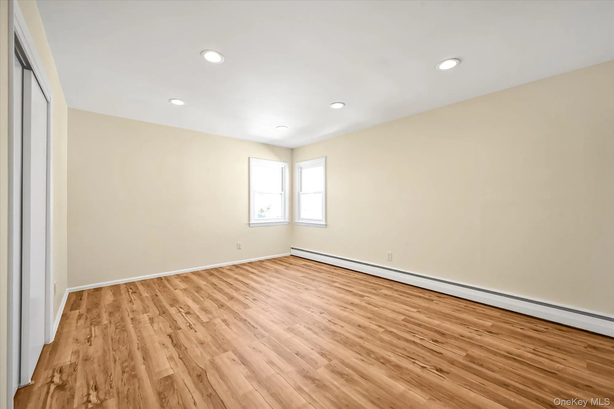 Unfurnished bedroom featuring a baseboard heating unit, recessed lighting, light wood-type flooring, and a closet Unfurnished bedroom featuring a baseboard heating unit, recessed lighting, light wood-type flooring, and a closet