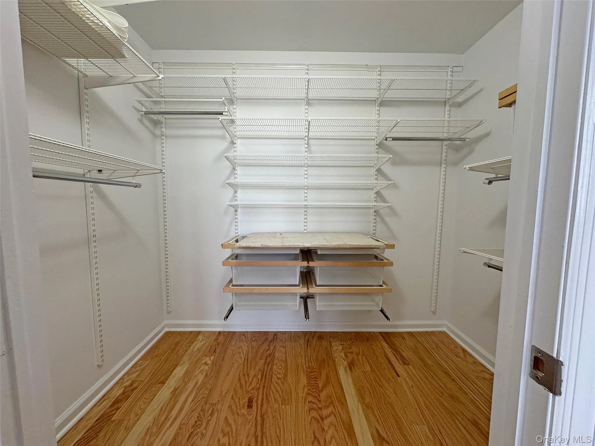 Large Walk in closet with light wood-style floors Large Walk in closet with light wood-style floors