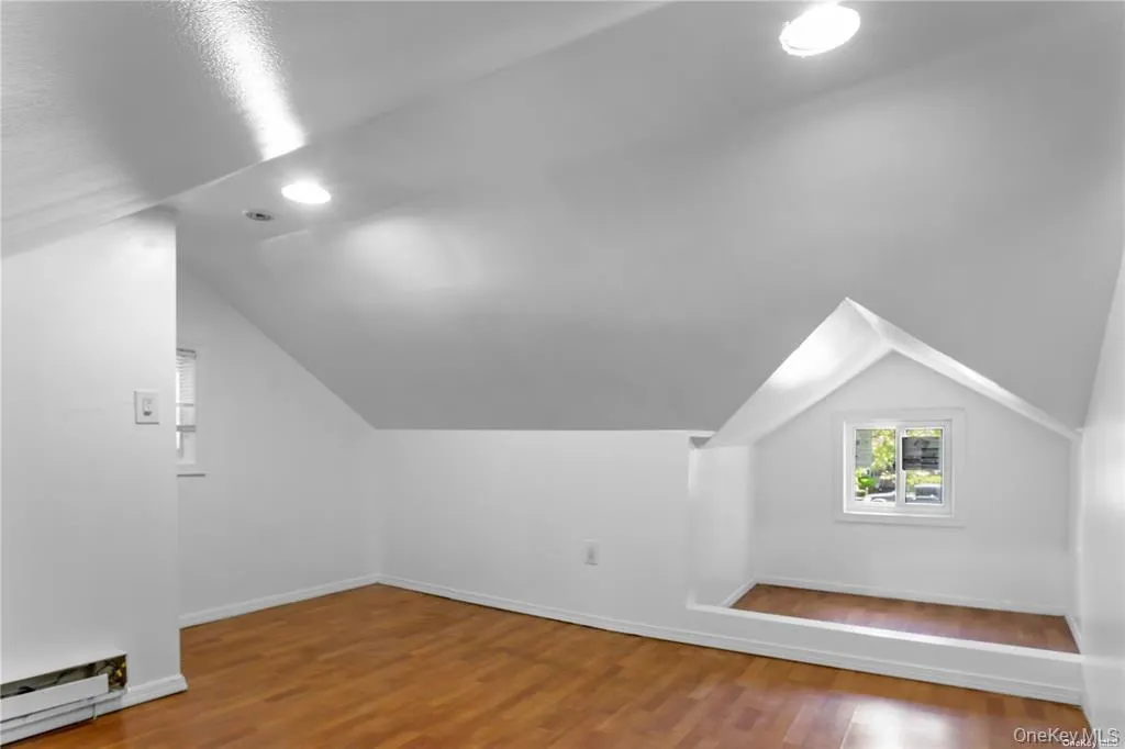 Additional living space with light wood finished floors, vaulted ceiling, and baseboard heating Additional living space with light wood finished floors, vaulted ceiling, and baseboard heating