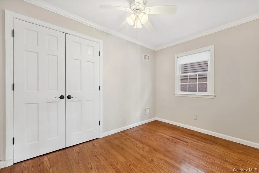 Unfurnished bedroom with crown molding, a closet, wood finished floors, and ceiling fan Unfurnished bedroom with crown molding, a closet, wood finished floors, and ceiling fan