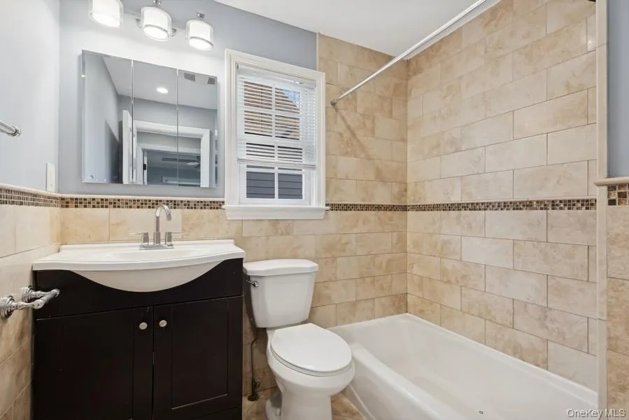 Full bath featuring vanity, shower / washtub combination, and tile walls Full bath featuring vanity, shower / washtub combination, and tile walls