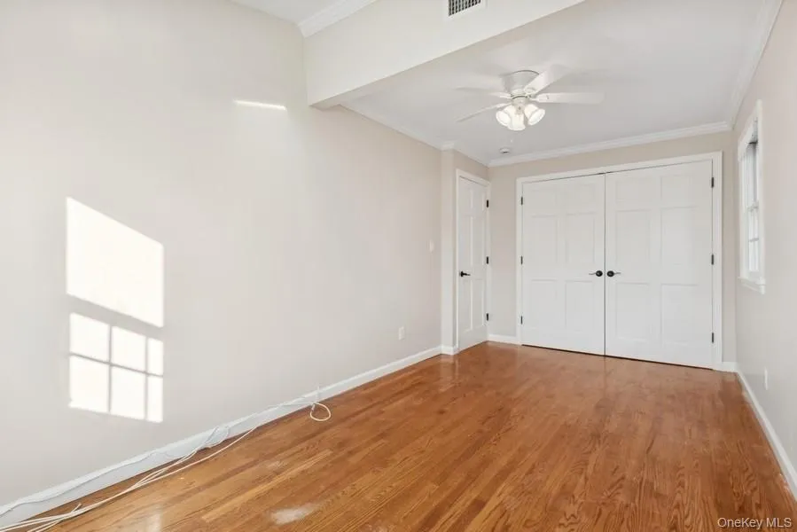 Unfurnished bedroom featuring crown molding, wood finished floors, a ceiling fan, and a closet Unfurnished bedroom featuring crown molding, wood finished floors, a ceiling fan, and a closet