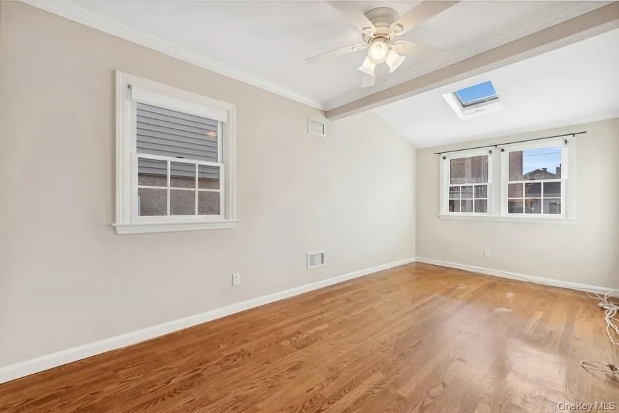 Spare room featuring crown molding, a skylight, wood finished floors, vaulted ceiling, and ceiling fan Spare room featuring crown molding, a skylight, wood finished floors, vaulted ceiling, and ceiling fan