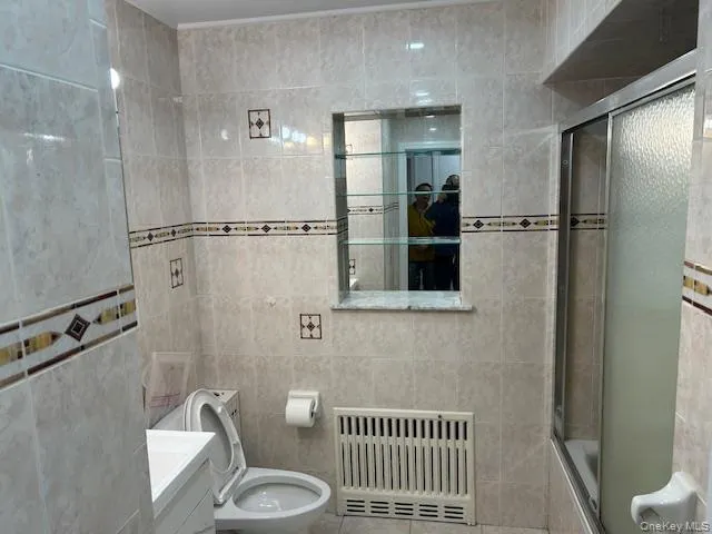 Full bath with radiator, tile walls, vanity, tiled shower / bath, and tile patterned flooring Full bath with radiator, tile walls, vanity, tiled shower / bath, and tile patterned flooring