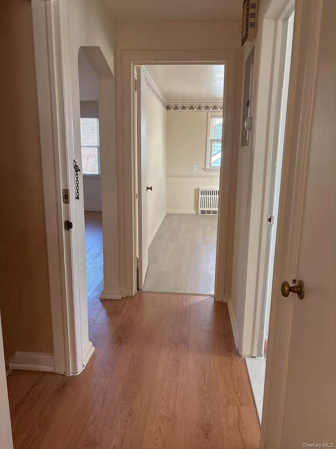 Corridor featuring light wood-style flooring, arched walkways, and radiator Corridor featuring light wood-style flooring, arched walkways, and radiator