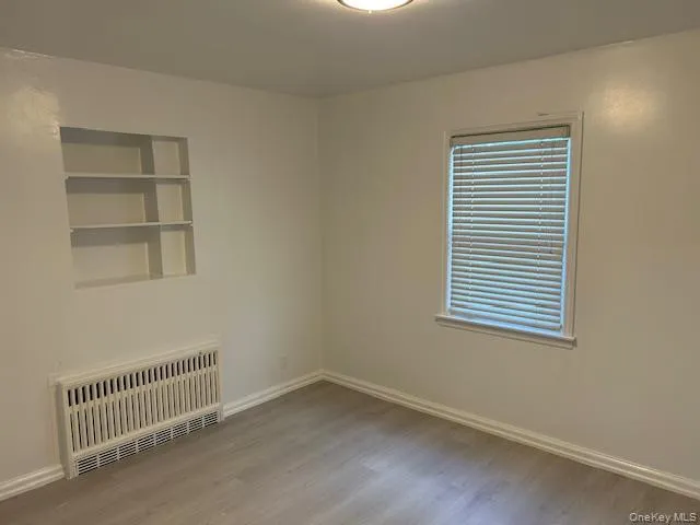 Unfurnished room with radiator heating unit and wood finished floors Unfurnished room with radiator heating unit and wood finished floors
