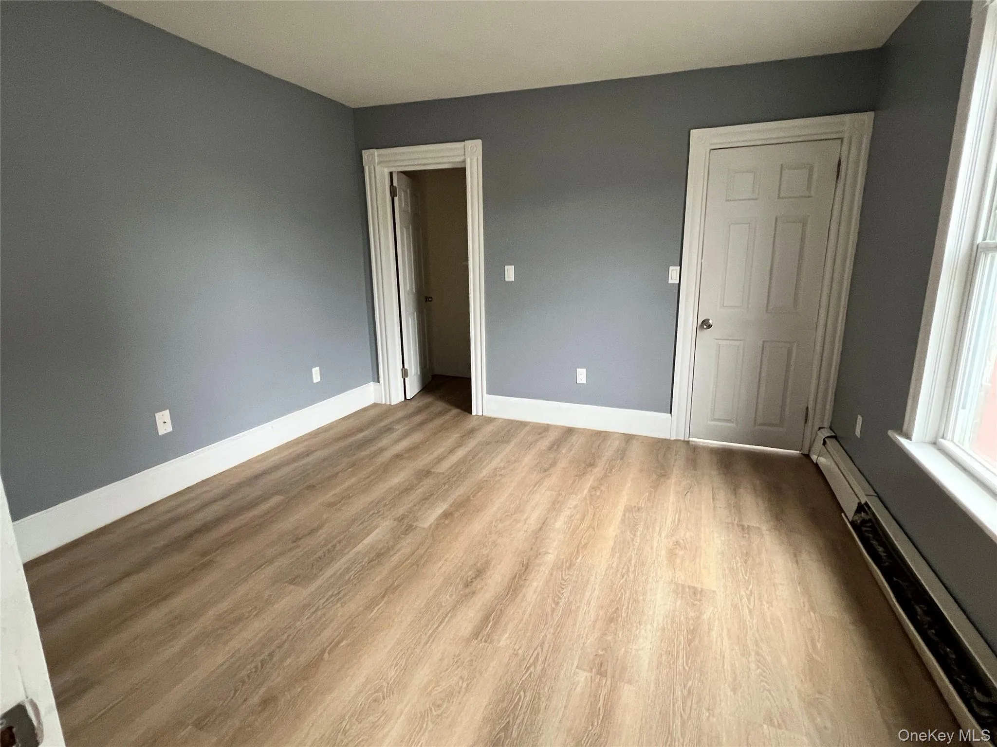 Unfurnished bedroom with a baseboard heating unit and light wood-type flooring Unfurnished bedroom with a baseboard heating unit and light wood-type flooring