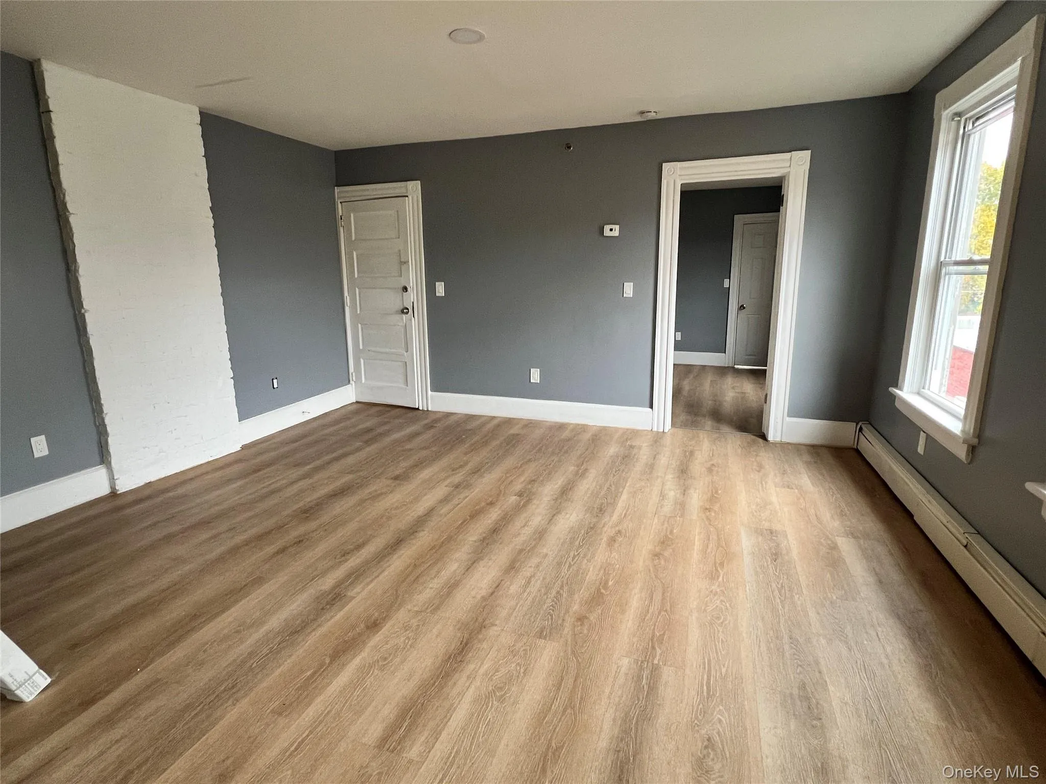 Spare room featuring a baseboard heating unit and light wood finished floors Spare room featuring a baseboard heating unit and light wood finished floors