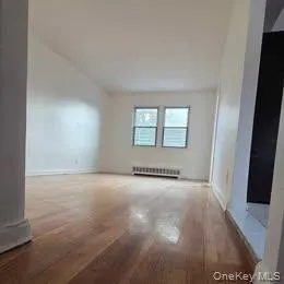 Unfurnished room with wood finished floors and radiator Unfurnished room with wood finished floors and radiator