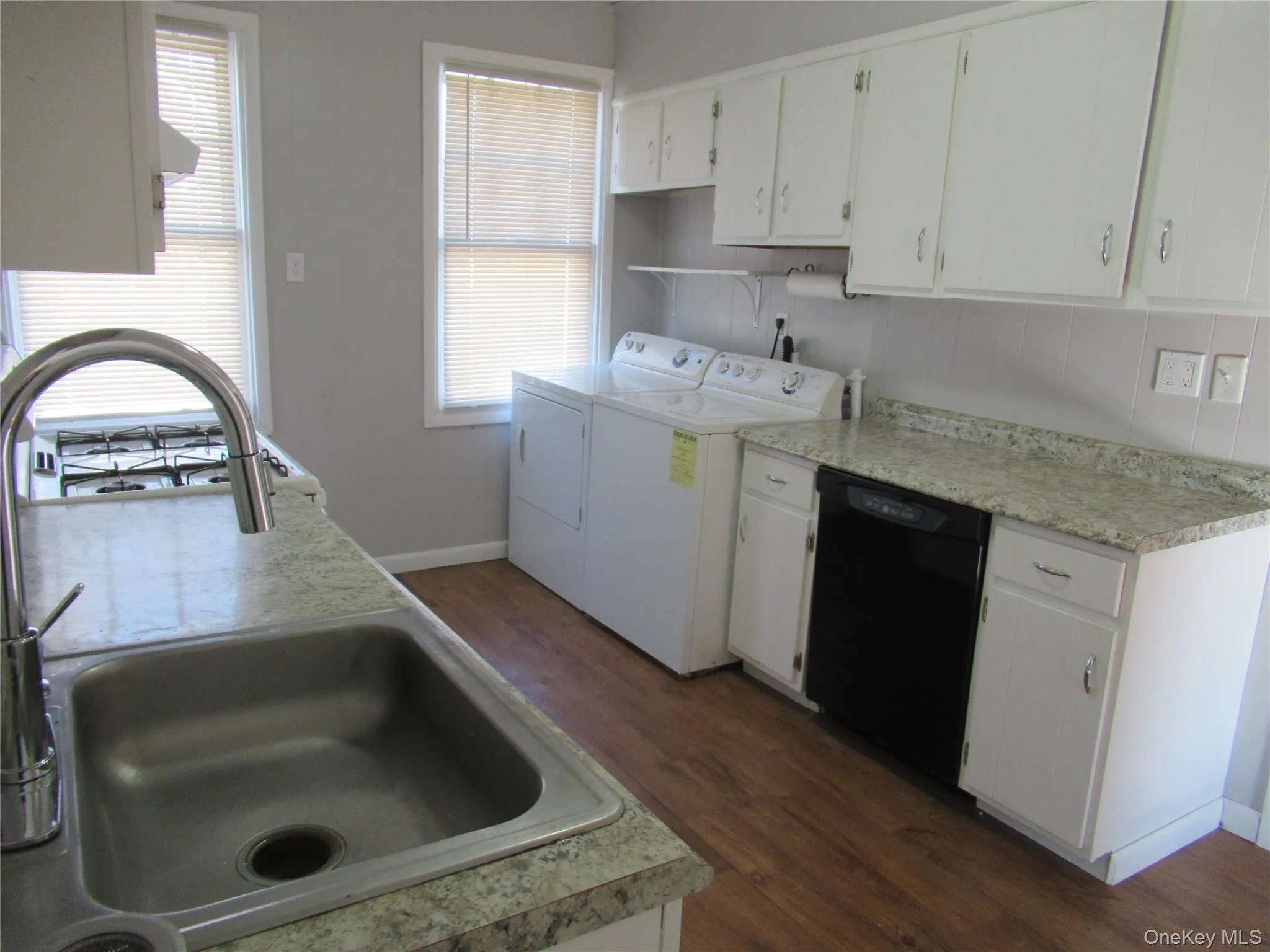Kitchen with wood finish floors, light countertops, and white cabinetry w/dryer Kitchen with wood finish floors, light countertops, and white cabinetry w/dryer