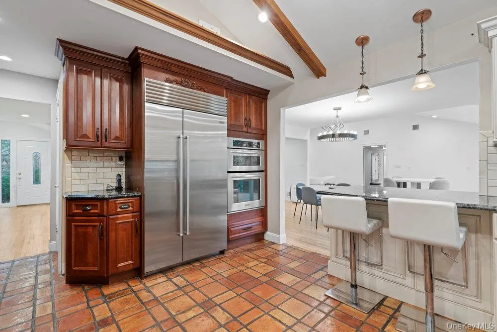 Kitchen featuring dark stone counters, appliances with stainless steel finishes, backsplash, decorative light fixtures, and recessed lighting Kitchen featuring dark stone counters, appliances with stainless steel finishes, backsplash, decorative light fixtures, and recessed lighting
