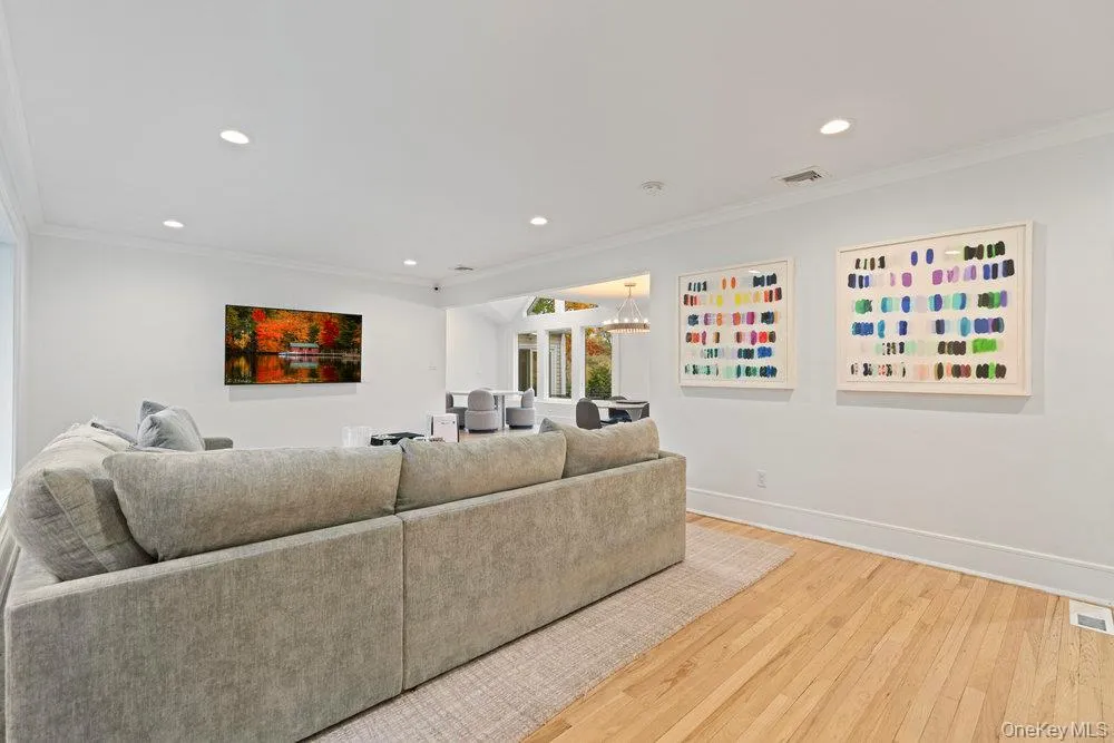 Living room with crown molding, light wood-type flooring, recessed lighting, and a chandelier Living room with crown molding, light wood-type flooring, recessed lighting, and a chandelier