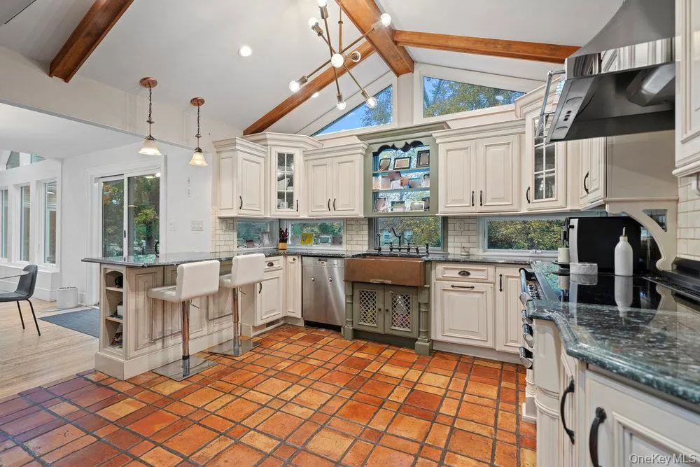 Kitchen featuring open shelves, beamed ceiling, decorative backsplash, a peninsula, and dark stone countertops Kitchen featuring open shelves, beamed ceiling, decorative backsplash, a peninsula, and dark stone countertops