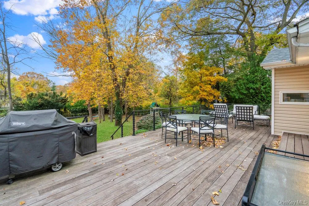 Wooden terrace featuring outdoor dining area, grilling area, and view of scattered trees Wooden terrace featuring outdoor dining area, grilling area, and view of scattered trees