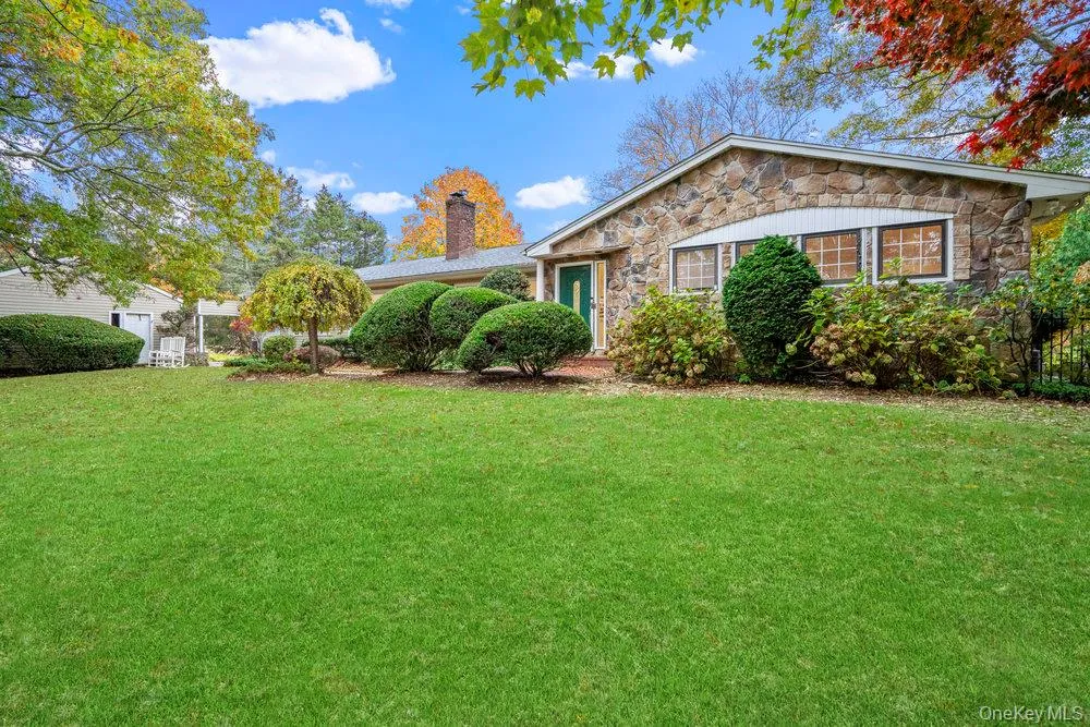 View of front facade with stone siding, a front lawn, and a chimney View of front facade with stone siding, a front lawn, and a chimney