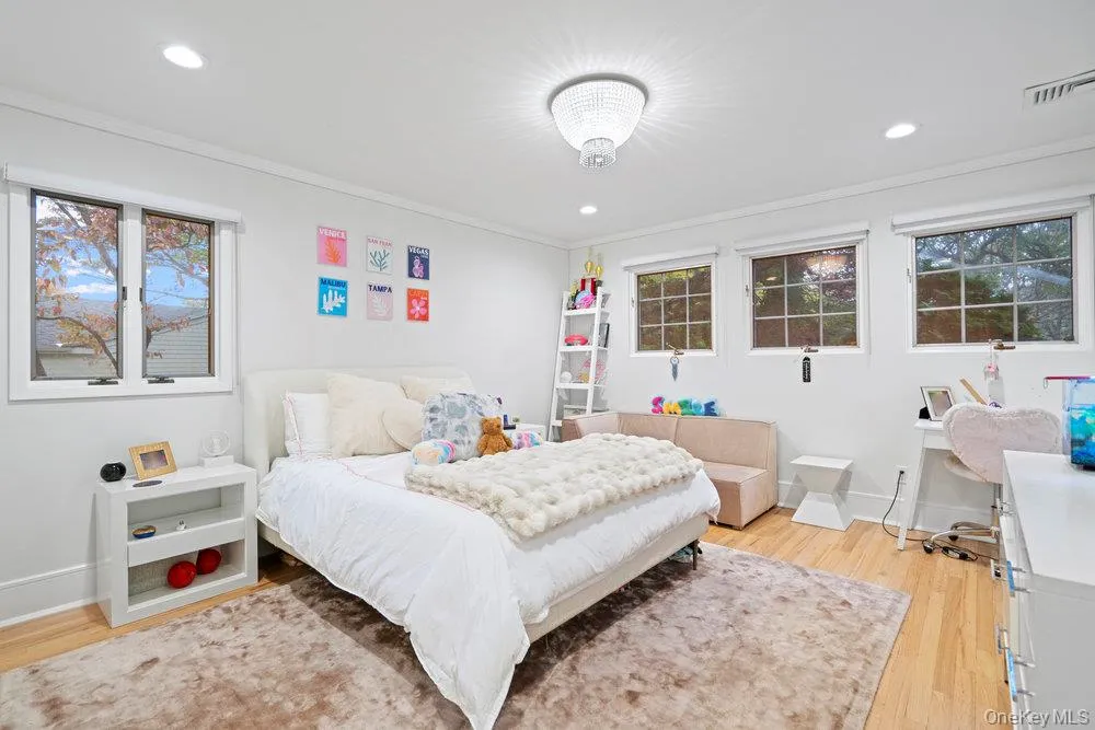 Bedroom with light wood-type flooring, multiple windows, ornamental molding, and recessed lighting Bedroom with light wood-type flooring, multiple windows, ornamental molding, and recessed lighting