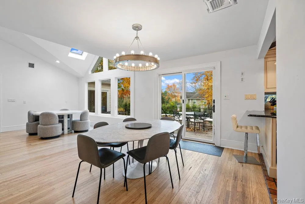 Dining area with a chandelier, light wood-style floors, a skylight, and high vaulted ceiling Dining area with a chandelier, light wood-style floors, a skylight, and high vaulted ceiling