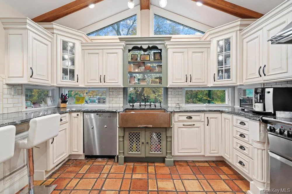 Kitchen with glass insert cabinets, dark stone countertops, appliances with stainless steel finishes, and tasteful backsplash Kitchen with glass insert cabinets, dark stone countertops, appliances with stainless steel finishes, and tasteful backsplash