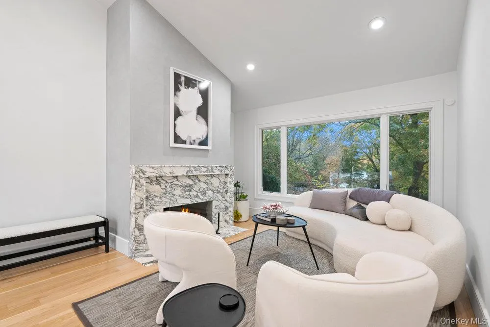 Living room with lofted ceiling, light wood finished floors, a high end fireplace, and recessed lighting Living room with lofted ceiling, light wood finished floors, a high end fireplace, and recessed lighting