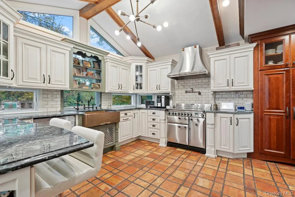 Kitchen with beam ceiling, glass insert cabinets, tasteful backsplash, open shelves, and wall chimney range hood Kitchen with beam ceiling, glass insert cabinets, tasteful backsplash, open shelves, and wall chimney range hood