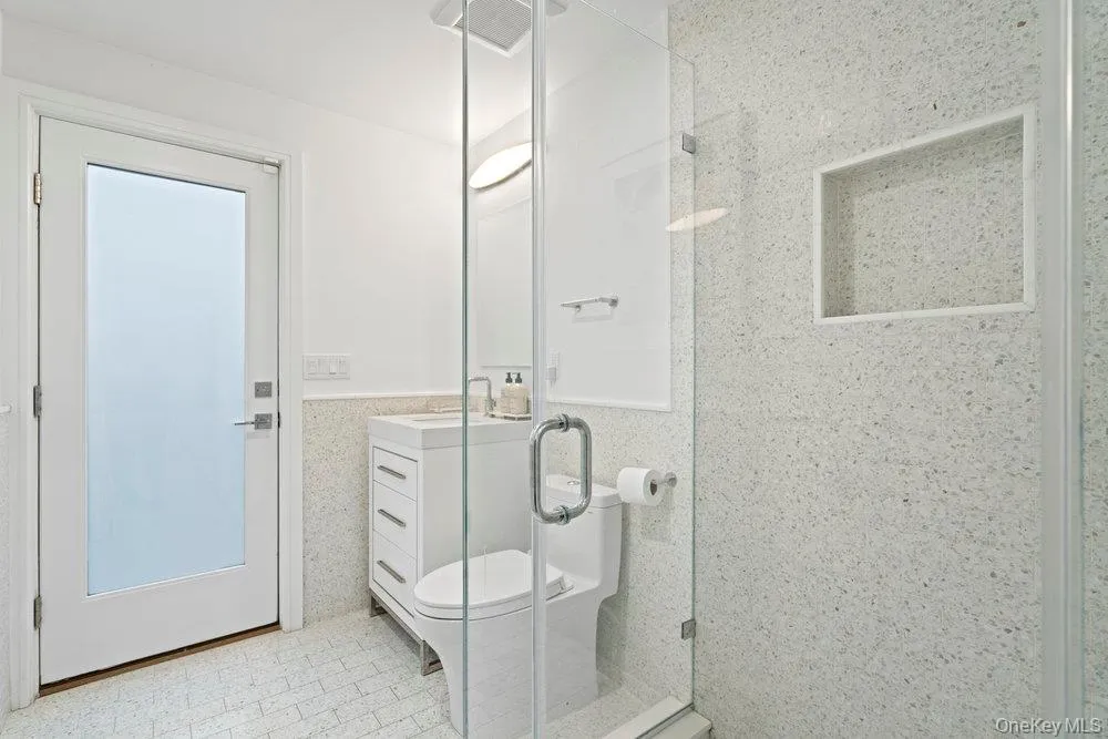 Full bath featuring a shower stall, vanity, wainscoting, and tile walls Full bath featuring a shower stall, vanity, wainscoting, and tile walls