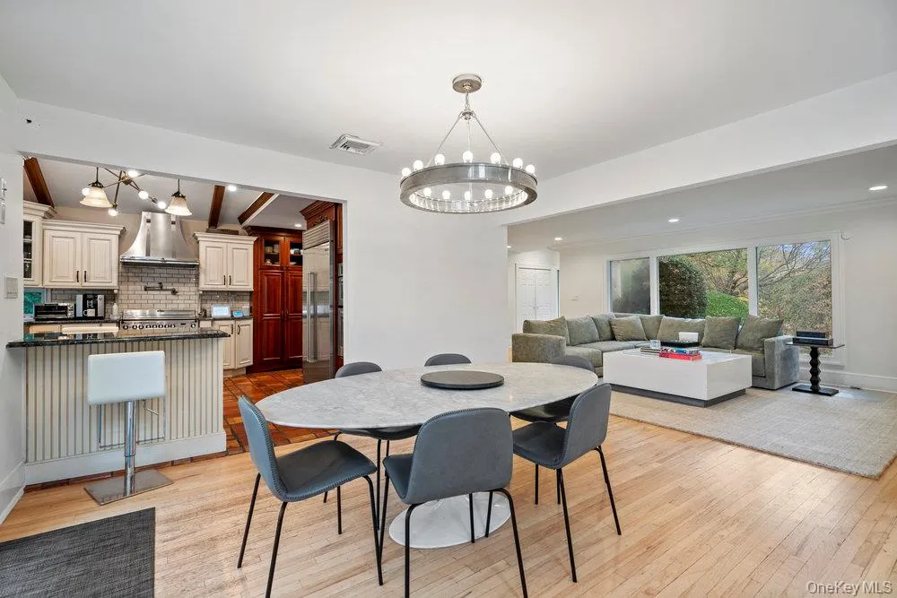 Dining area featuring a chandelier, beamed ceiling, and light wood-style flooring Dining area featuring a chandelier, beamed ceiling, and light wood-style flooring