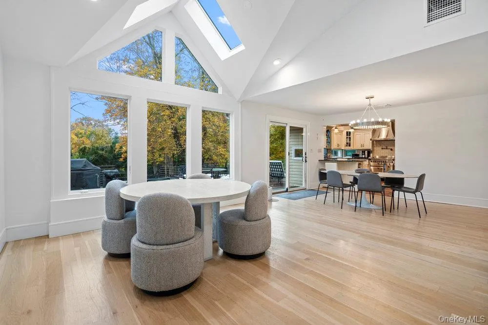 Dining room featuring high vaulted ceiling, a skylight, light wood-style flooring, a chandelier, and recessed lighting Dining room featuring high vaulted ceiling, a skylight, light wood-style flooring, a chandelier, and recessed lighting