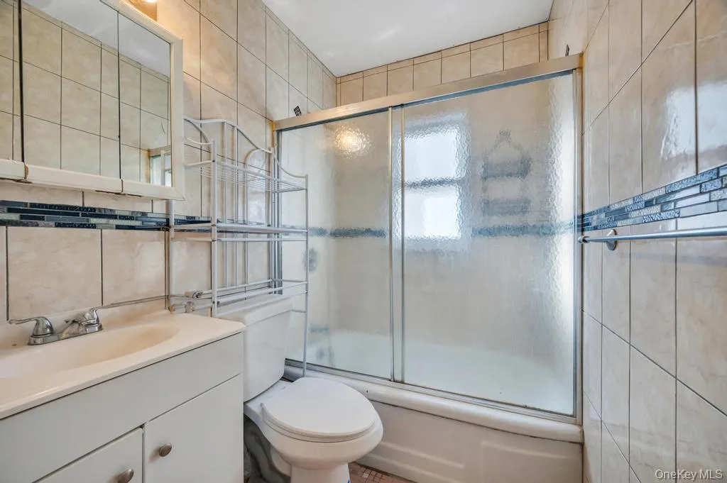 Full bath with tile walls, shower / bath combination with glass door, and vanity Full bath with tile walls, shower / bath combination with glass door, and vanity