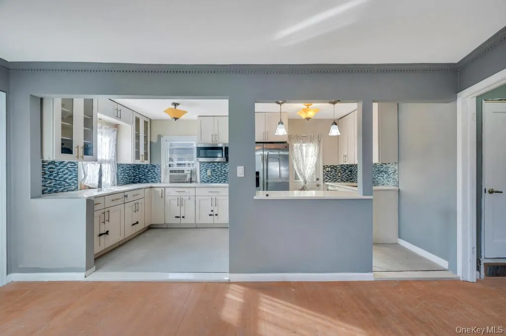 Kitchen featuring decorative backsplash, glass insert cabinets, stainless steel appliances, and light wood-style flooring Kitchen featuring decorative backsplash, glass insert cabinets, stainless steel appliances, and light wood-style flooring