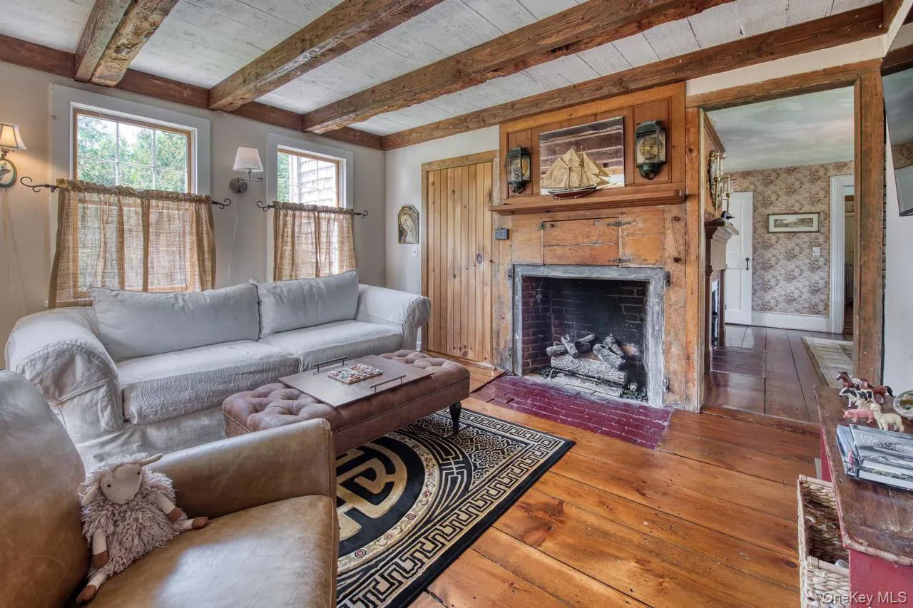 Living room with hardwood / wood-style flooring, beam ceiling, and a fireplace with flush hearth Living room with hardwood / wood-style flooring, beam ceiling, and a fireplace with flush hearth