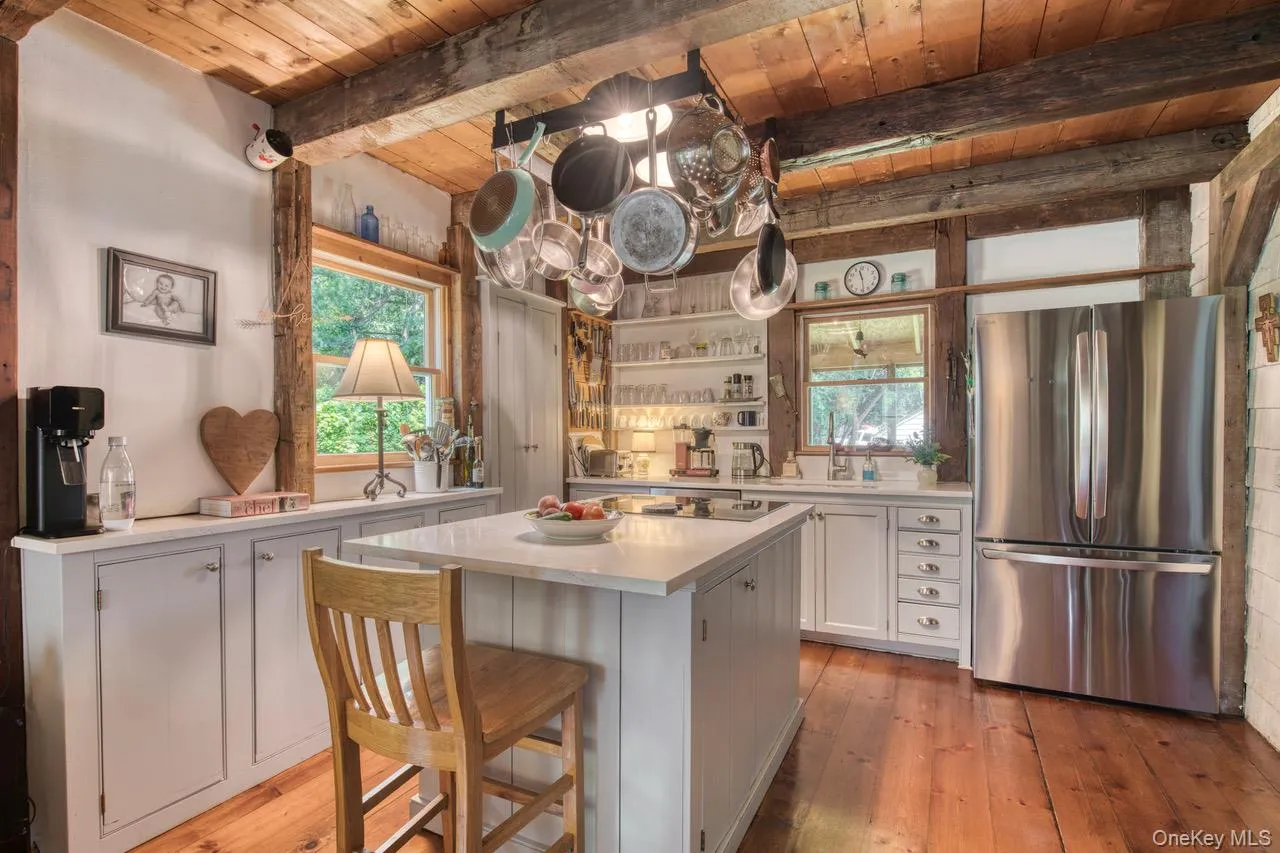 Kitchen with white cabinetry, open shelves, freestanding refrigerator, a wooden ceiling with exposed beams, and light wood finished floors Kitchen with white cabinetry, open shelves, freestanding refrigerator, a wooden ceiling with exposed beams, and light wood finished floors