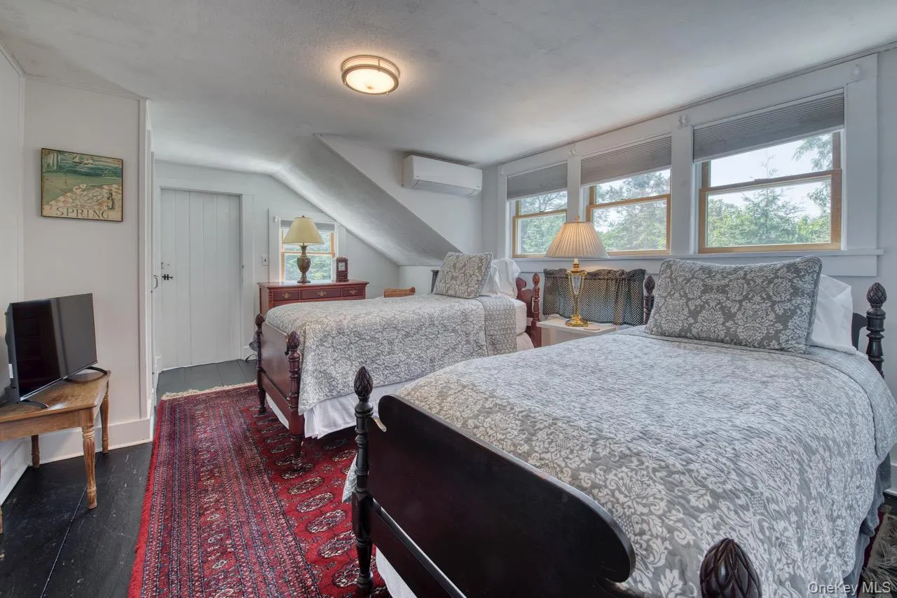 Bedroom featuring dark wood-type flooring and a wall mounted air conditioner Bedroom featuring dark wood-type flooring and a wall mounted air conditioner