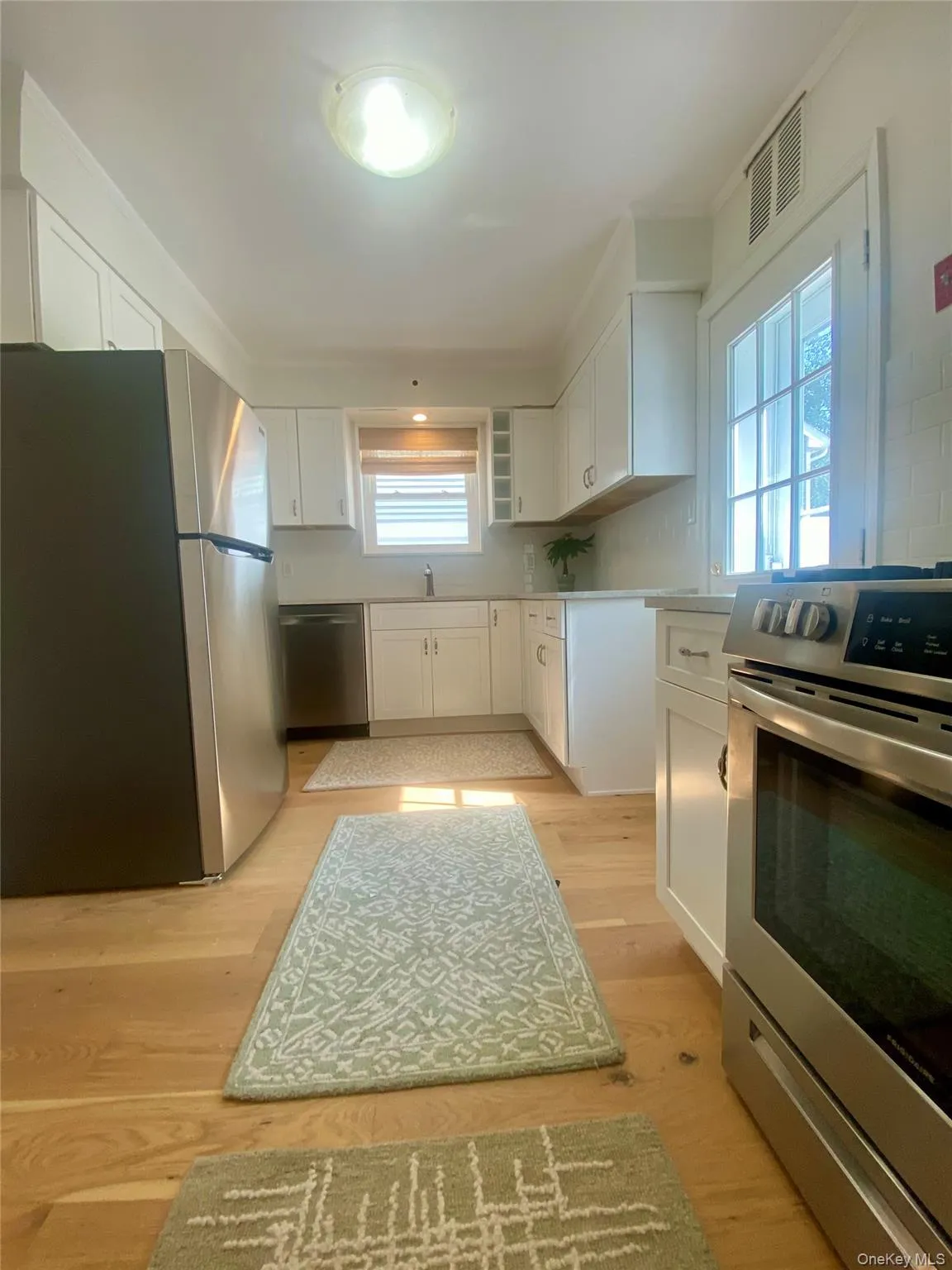 Kitchen with white cabinets, appliances with stainless steel finishes, open shelves, and light wood-style flooring Kitchen with white cabinets, appliances with stainless steel finishes, open shelves, and light wood-style flooring