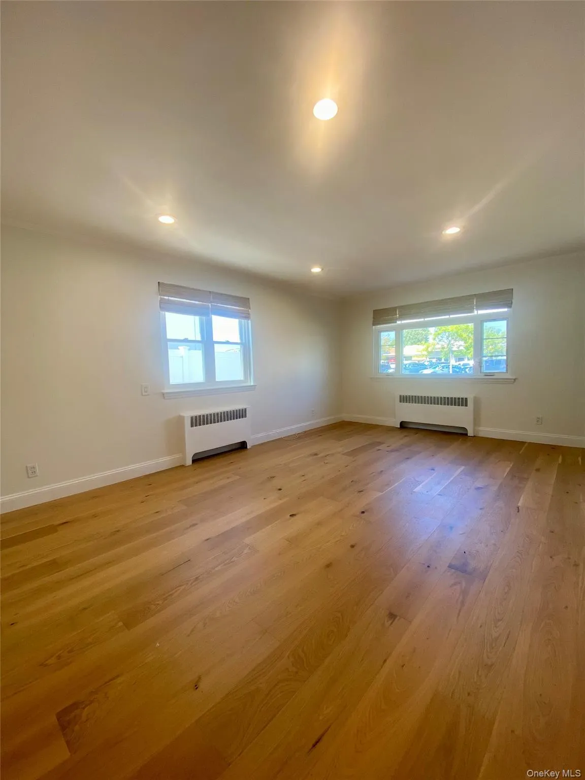 Spare room with radiator heating unit, recessed lighting, light wood-style flooring, and crown molding Spare room with radiator heating unit, recessed lighting, light wood-style flooring, and crown molding