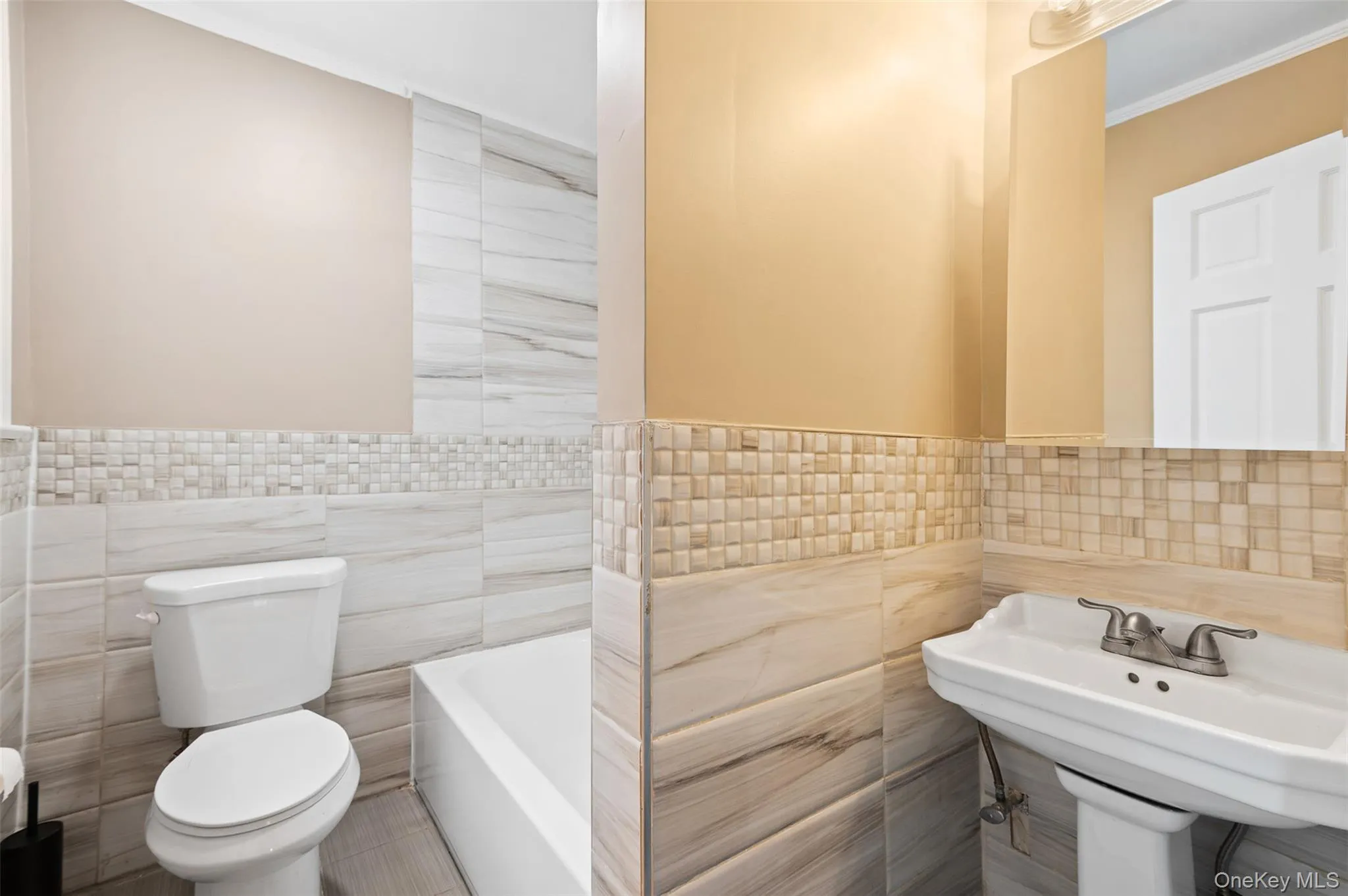 Full bathroom with tile walls, a tub, crown molding, and wainscoting Full bathroom with tile walls, a tub, crown molding, and wainscoting