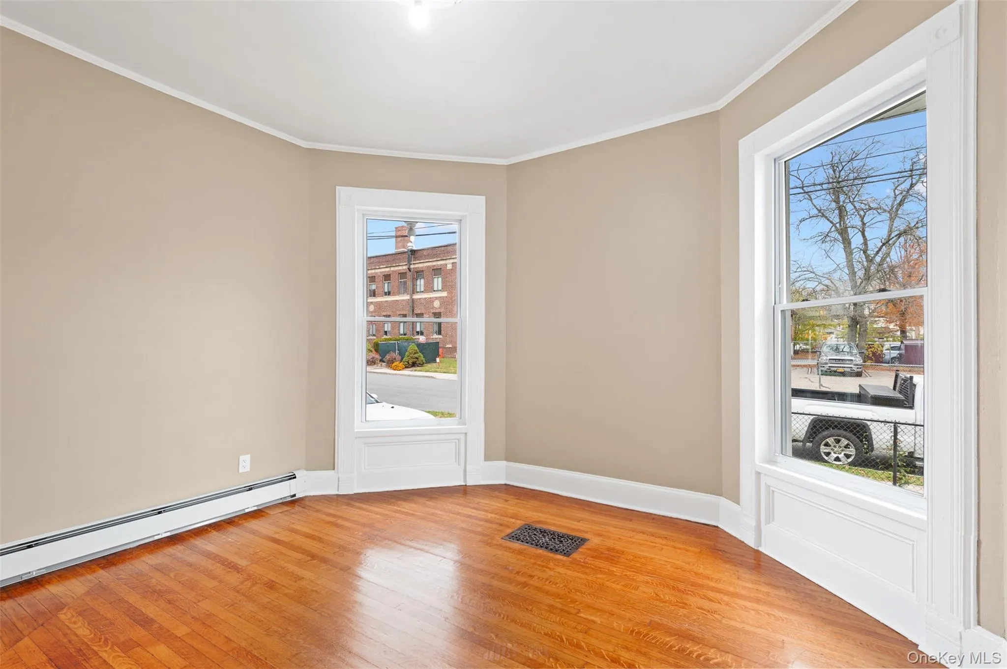 Unfurnished room with light wood-style floors, ornamental molding, and a baseboard radiator Unfurnished room with light wood-style floors, ornamental molding, and a baseboard radiator
