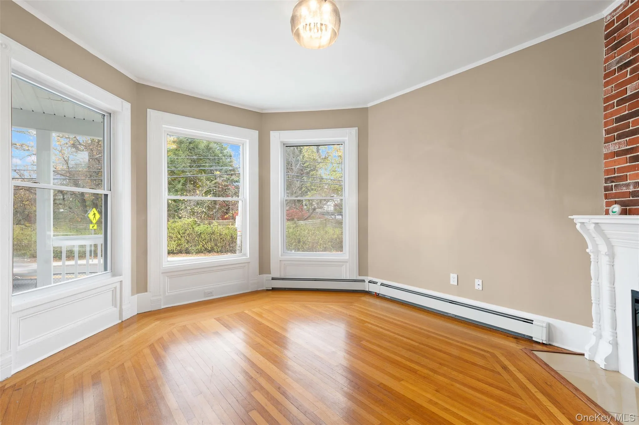 Spare room featuring crown molding, light wood-style floors, a fireplace with flush hearth, and a baseboard heating unit Spare room featuring crown molding, light wood-style floors, a fireplace with flush hearth, and a baseboard heating unit