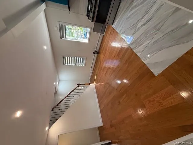 Unfurnished living room featuring light wood finished floors, stairs, recessed lighting, and baseboard heating Unfurnished living room featuring light wood finished floors, stairs, recessed lighting, and baseboard heating