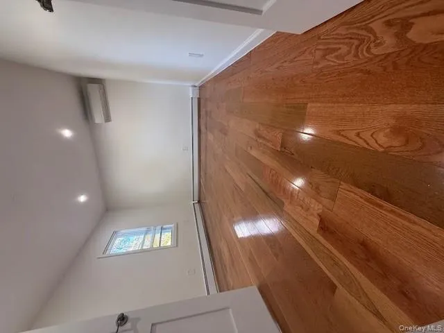 Spare room with light wood-style floors, a baseboard radiator, recessed lighting, and a wall mounted air conditioner Spare room with light wood-style floors, a baseboard radiator, recessed lighting, and a wall mounted air conditioner